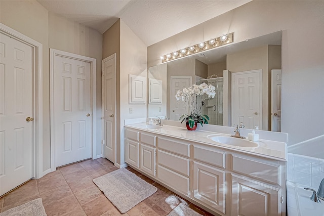 bathroom featuring double vanity, a stall shower, a sink, and tile patterned floors