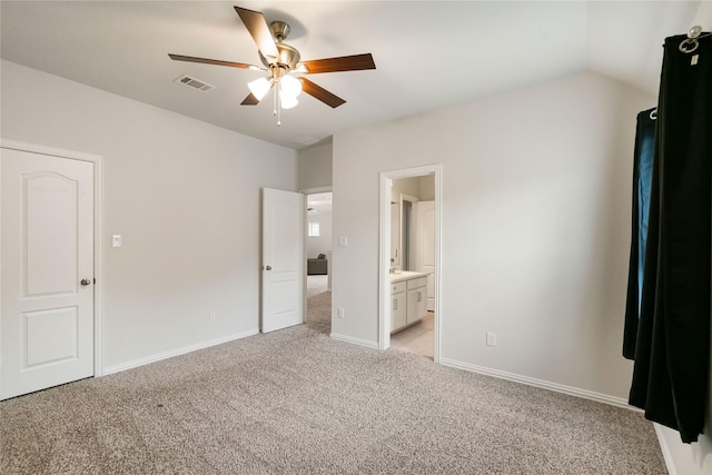 unfurnished bedroom featuring light carpet, connected bathroom, lofted ceiling, and ceiling fan