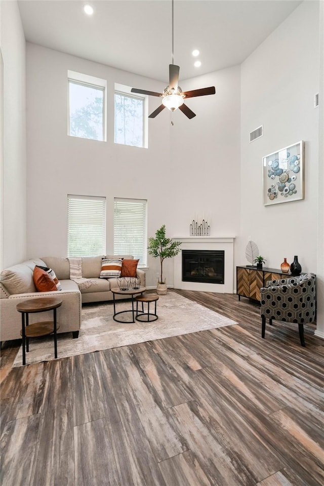 living room with a high ceiling, plenty of natural light, hardwood / wood-style floors, and ceiling fan