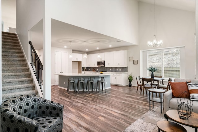 living room with sink, wood-type flooring, a chandelier, and a high ceiling