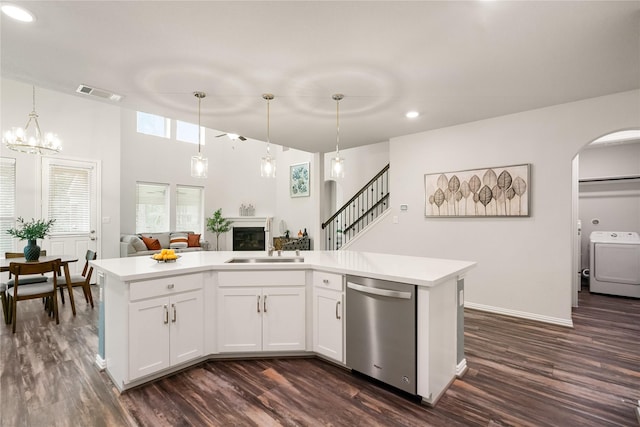 kitchen featuring pendant lighting, sink, white cabinets, washer / dryer, and stainless steel dishwasher