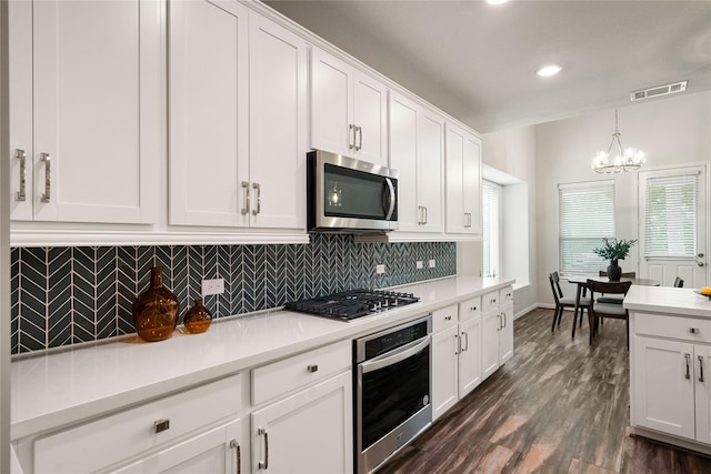 kitchen with white cabinetry, decorative backsplash, decorative light fixtures, and appliances with stainless steel finishes