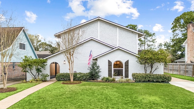 view of front facade featuring brick siding, a front yard, and fence