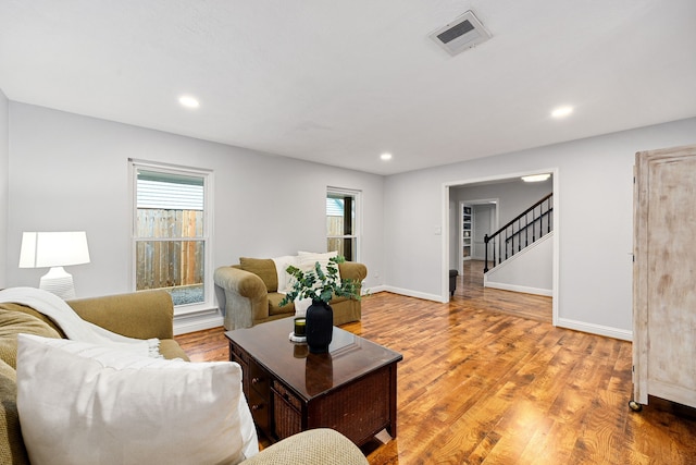 living area featuring recessed lighting, visible vents, light wood-style floors, baseboards, and stairs