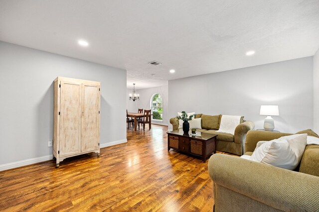 living room featuring recessed lighting, wood finished floors, visible vents, baseboards, and an inviting chandelier