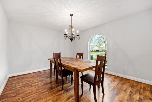 dining room featuring a notable chandelier, baseboards, and wood finished floors