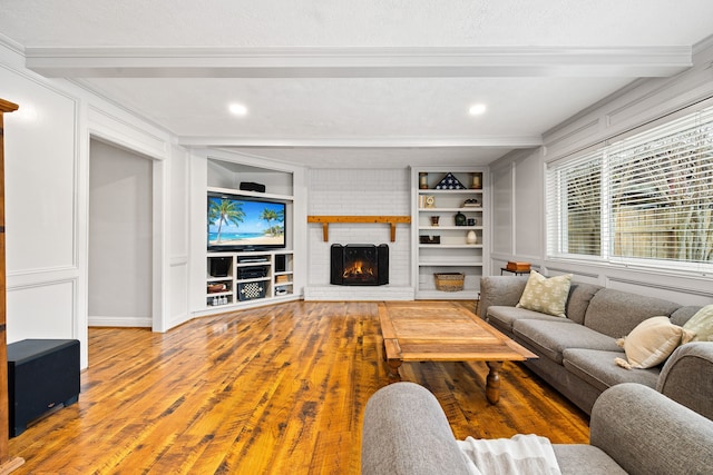 living area with recessed lighting, wood finished floors, built in features, a brick fireplace, and beam ceiling