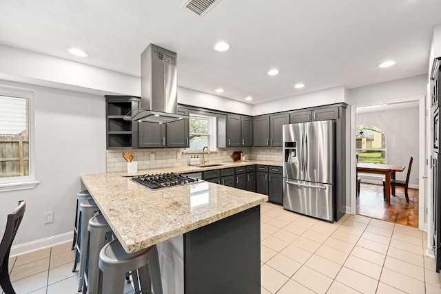 kitchen with island range hood, stainless steel appliances, a peninsula, a sink, and visible vents