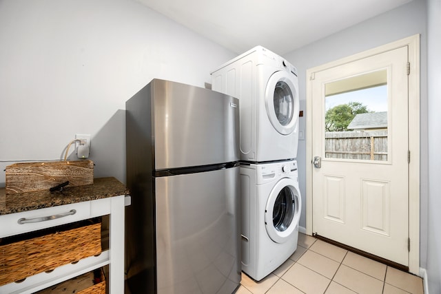 washroom featuring stacked washing maching and dryer, laundry area, and light tile patterned flooring