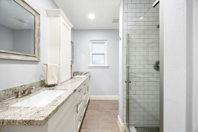 bathroom featuring baseboards, double vanity, a sink, and a shower stall