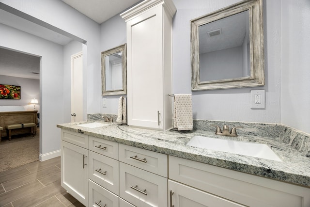 bathroom featuring double vanity, wood tiled floor, a sink, and ensuite bathroom