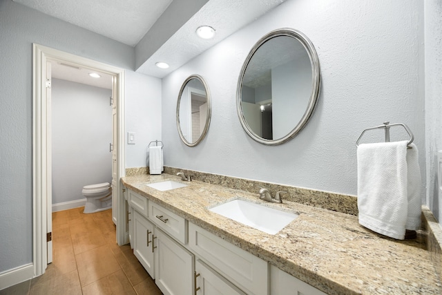 bathroom with recessed lighting, a sink, toilet, and double vanity