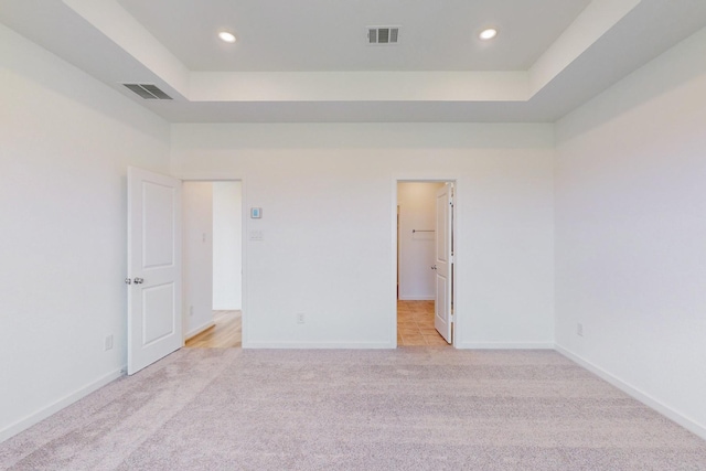 carpeted spare room featuring a towering ceiling and a tray ceiling