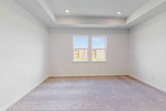 carpeted empty room with a tray ceiling