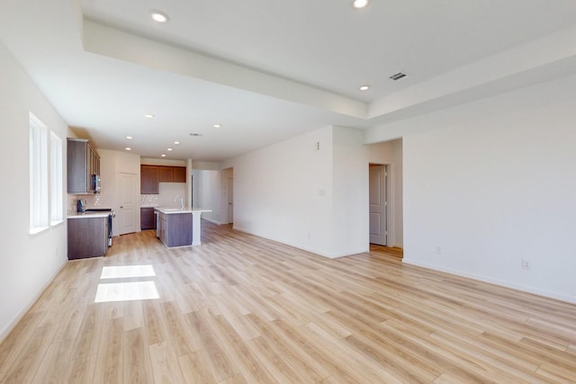 unfurnished living room featuring sink and light hardwood / wood-style flooring