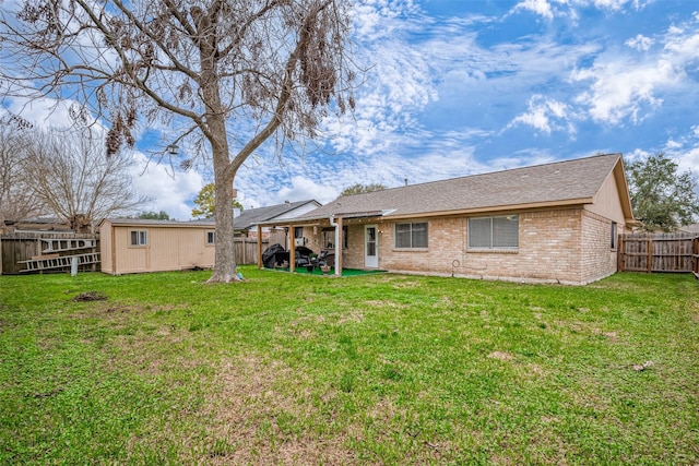 rear view of property featuring a patio, brick siding, a lawn, and a fenced backyard