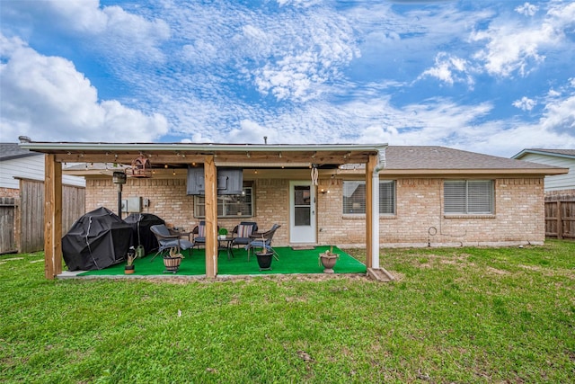 rear view of house featuring brick siding, fence, a patio, and a lawn