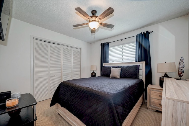 bedroom featuring a closet, light colored carpet, ceiling fan, and a textured ceiling