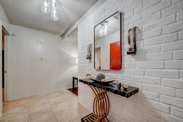 hallway with baseboards, a textured ceiling, brick wall, and light tile patterned flooring