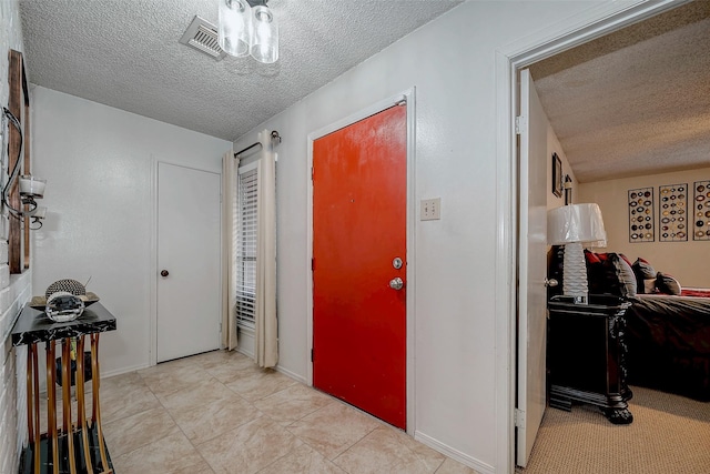 foyer entrance with light tile patterned floors, visible vents, and a textured ceiling