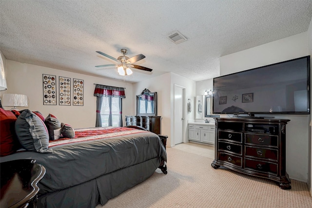 bedroom with light carpet, visible vents, a ceiling fan, connected bathroom, and a textured ceiling