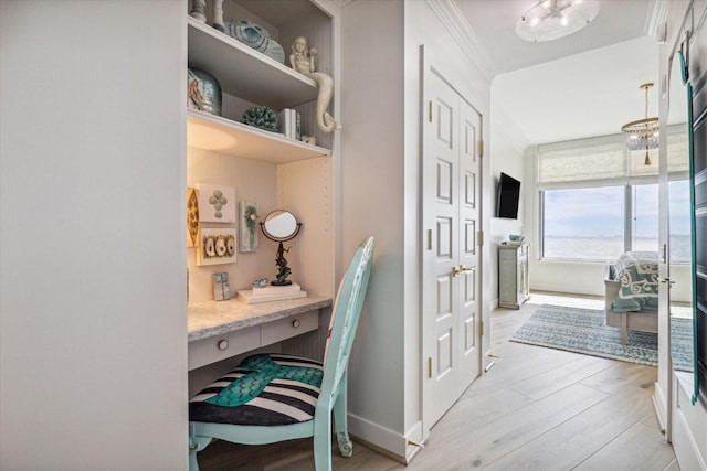 hall with baseboards, an inviting chandelier, and light wood-style floors