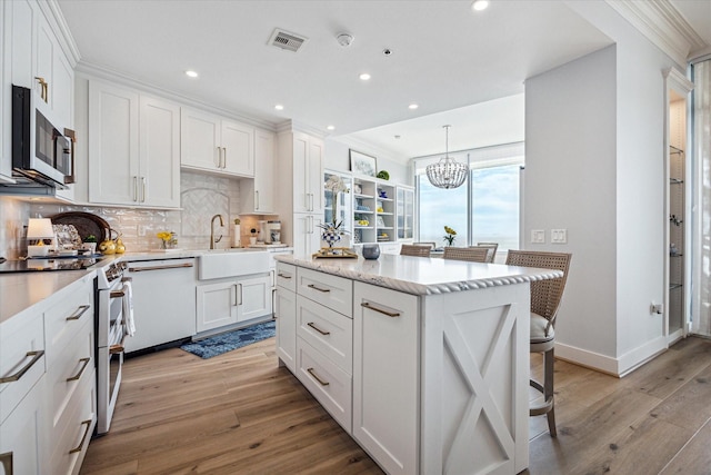 kitchen featuring white cabinets, appliances with stainless steel finishes, visible vents, and pendant lighting