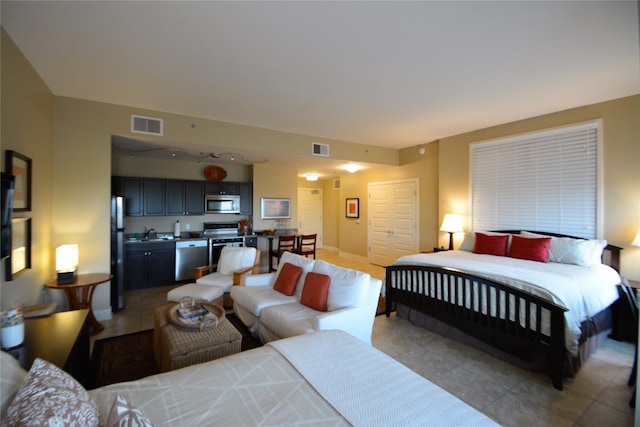 bedroom featuring light tile patterned floors, freestanding refrigerator, visible vents, and baseboards