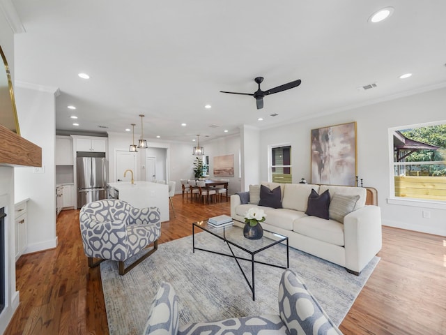 living room featuring ornamental molding, ceiling fan, and light hardwood / wood-style flooring