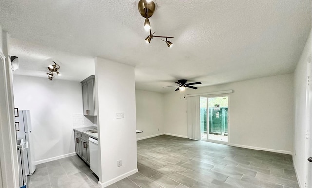 kitchen featuring tasteful backsplash, gray cabinets, dishwasher, and ceiling fan