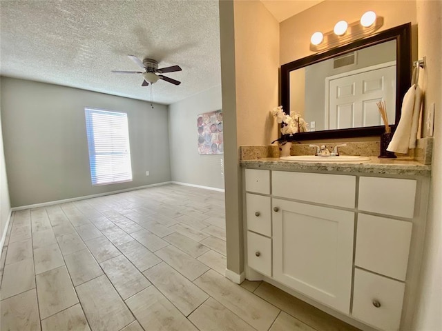 bathroom featuring vanity, a ceiling fan, baseboards, visible vents, and a textured ceiling