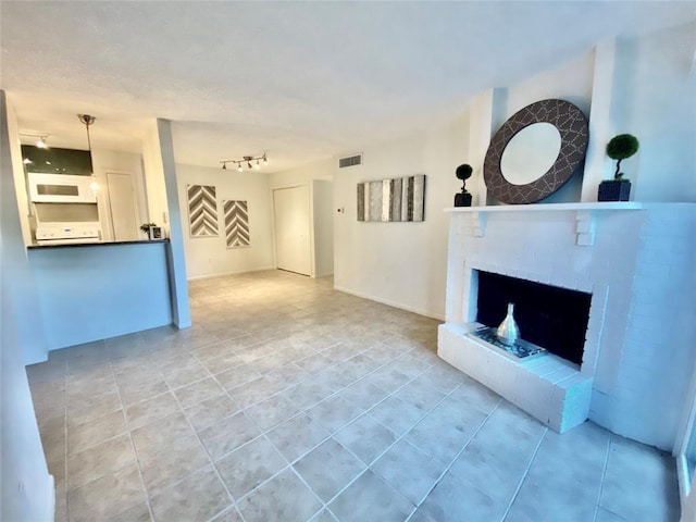 unfurnished living room featuring tile patterned floors, visible vents, a fireplace, and rail lighting