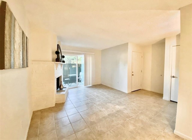 spare room featuring light tile patterned floors, a textured ceiling, and a fireplace