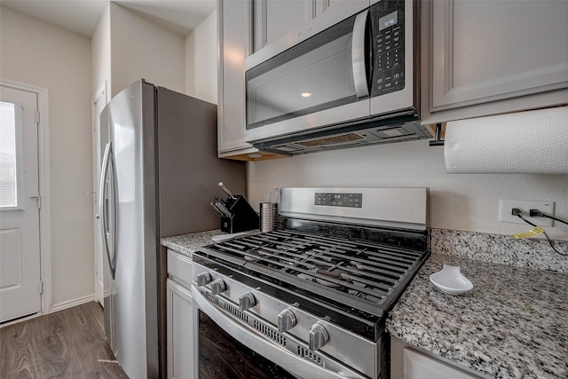 kitchen featuring light stone counters, dark hardwood / wood-style flooring, and stainless steel appliances