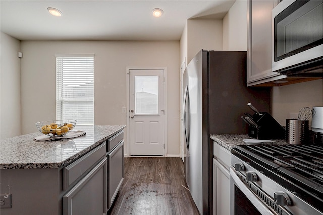 kitchen with gray cabinetry, light stone counters, a center island, and appliances with stainless steel finishes