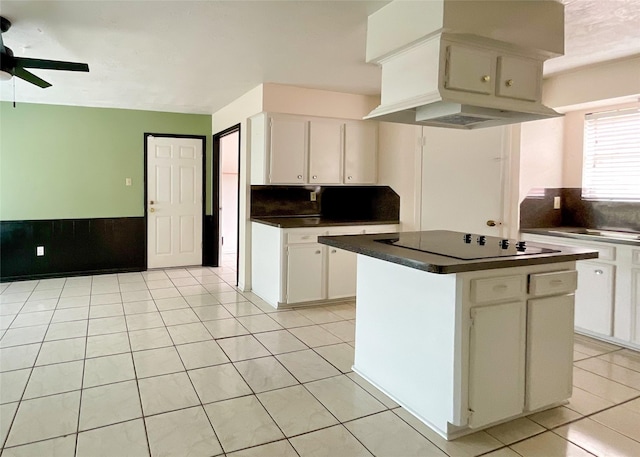 kitchen featuring a center island, light tile patterned floors, black electric cooktop, ceiling fan, and white cabinets