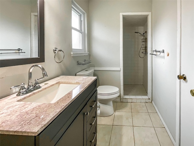 bathroom with vanity, toilet, tile patterned flooring, and a tile shower