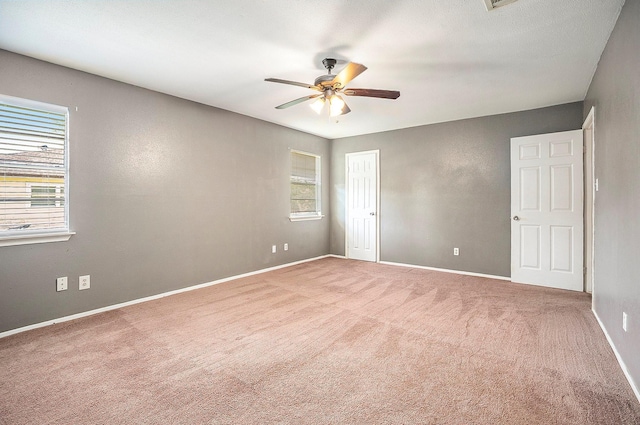 carpeted spare room featuring a healthy amount of sunlight and ceiling fan