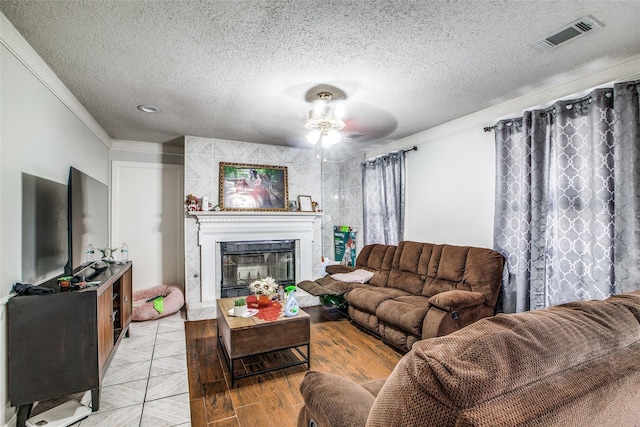 living room featuring crown molding, ceiling fan, light hardwood / wood-style floors, and a textured ceiling