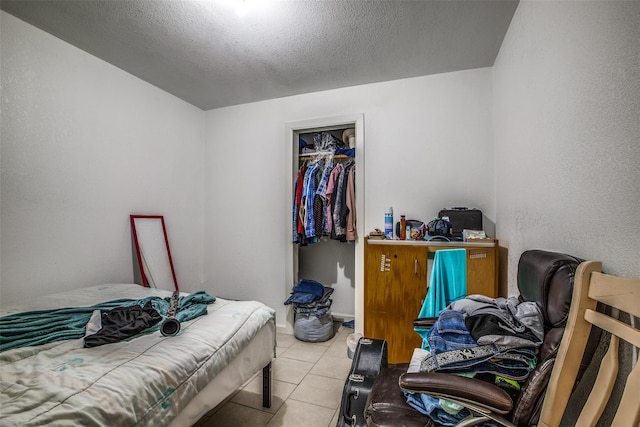 bedroom featuring light tile patterned flooring, a textured ceiling, and a closet