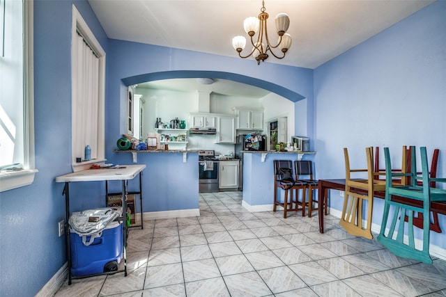 kitchen with a breakfast bar area, white cabinetry, stainless steel range, decorative light fixtures, and kitchen peninsula