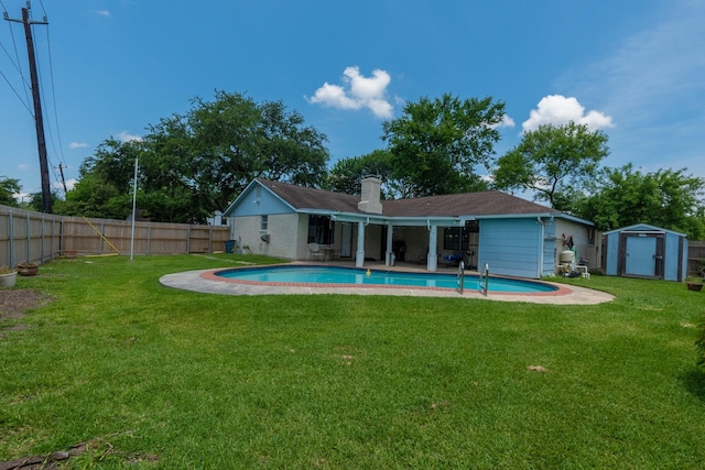 rear view of property featuring a yard, a fenced in pool, and a shed