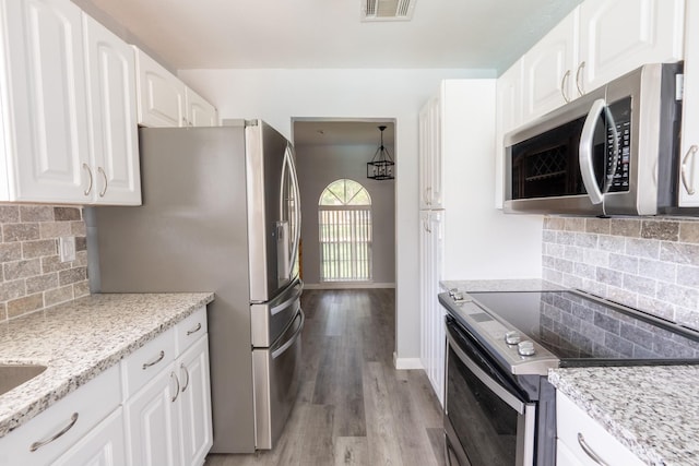 kitchen featuring light hardwood / wood-style flooring, white cabinetry, backsplash, stainless steel appliances, and light stone countertops