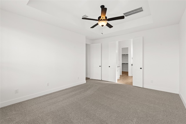 32626 Fly Fish Way, Fulshear, TX 77441 - unfurnished bedroom with light colored carpet, a tray ceiling, baseboards, and ceiling fan