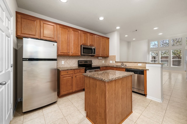 kitchen with light tile patterned floors, a kitchen island, stainless steel appliances, and dark stone counters