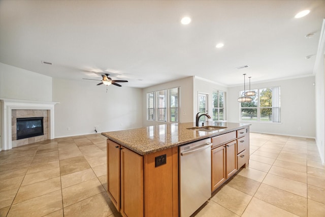 kitchen featuring visible vents, a center island with sink, dishwasher, a tile fireplace, and a sink