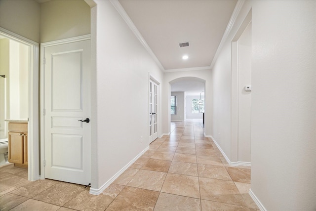 hall with baseboards, arched walkways, visible vents, and ornamental molding