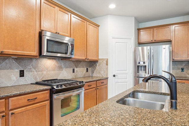 kitchen featuring dark stone counters, recessed lighting, a sink, appliances with stainless steel finishes, and tasteful backsplash