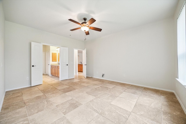 unfurnished bedroom with ceiling fan, ensuite bathroom, and baseboards