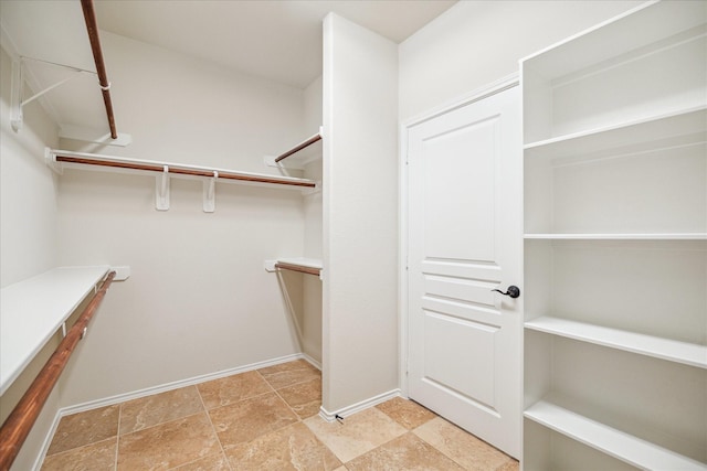 spacious closet featuring stone finish floor